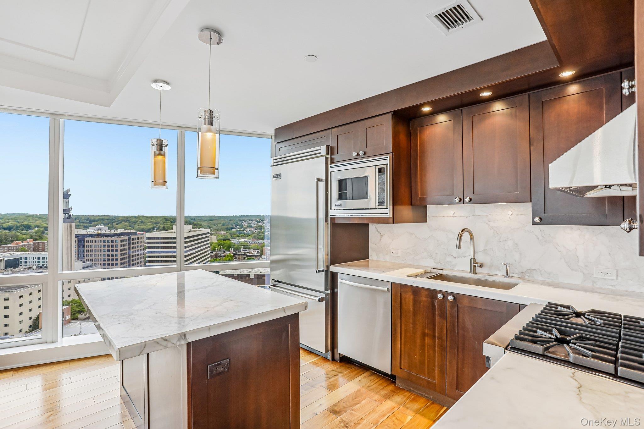 1 Renaissance Square, Unit 25G White Plains, NY 10601 - Photo 4 of 22 Kitchen featuring floor-to-ceiling windows, dark wood cabinetry, integrated stainless steel appliances, a gas cooktop, and marble countertops with a matching backsplash