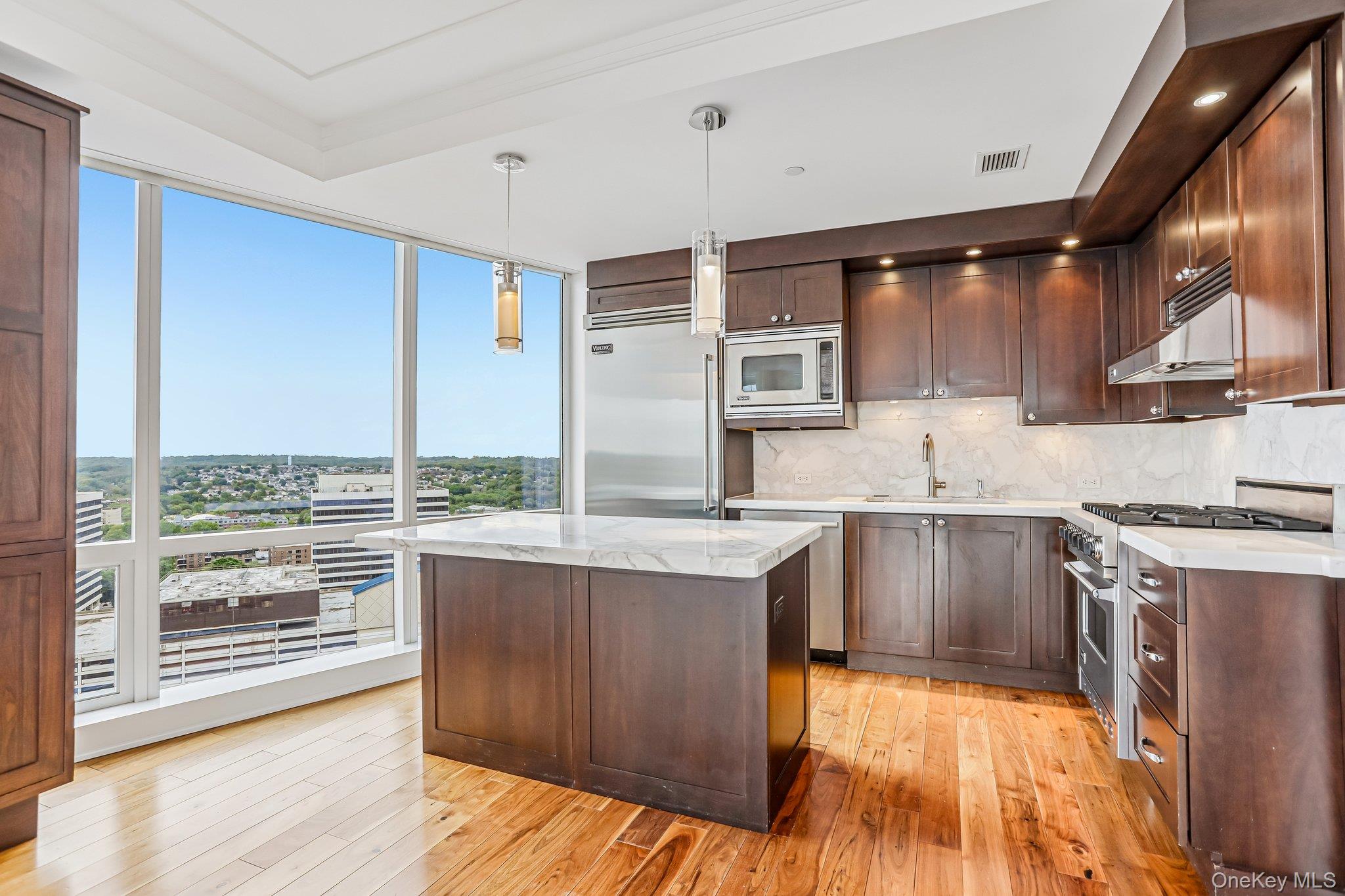 1 Renaissance Square, Unit 25G White Plains, NY 10601 - Photo 5 of 22 Kitchen featuring floor-to-ceiling windows, dark wood cabinetry, integrated stainless steel appliances, a gas cooktop, and marble countertops with a matching backsplash