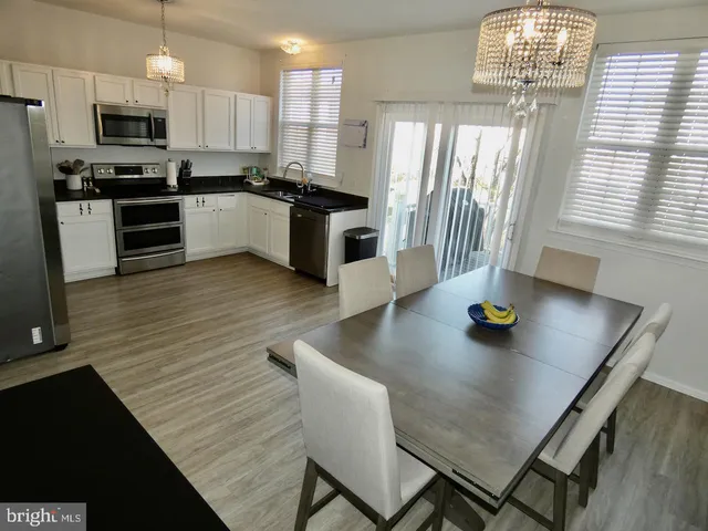 a kitchen with stainless steel appliances a dining table chairs stove refrigerator and cabinets