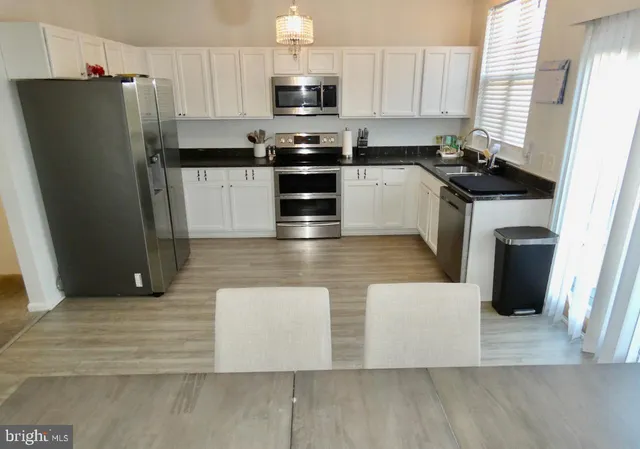 a kitchen with stainless steel appliances a refrigerator a stove a sink and white cabinets