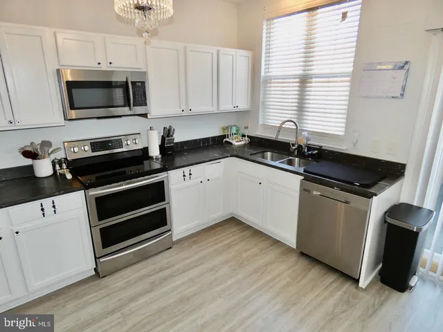 a kitchen with granite countertop a sink and steel appliances