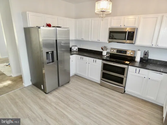 a kitchen with granite countertop a refrigerator and a stove top oven