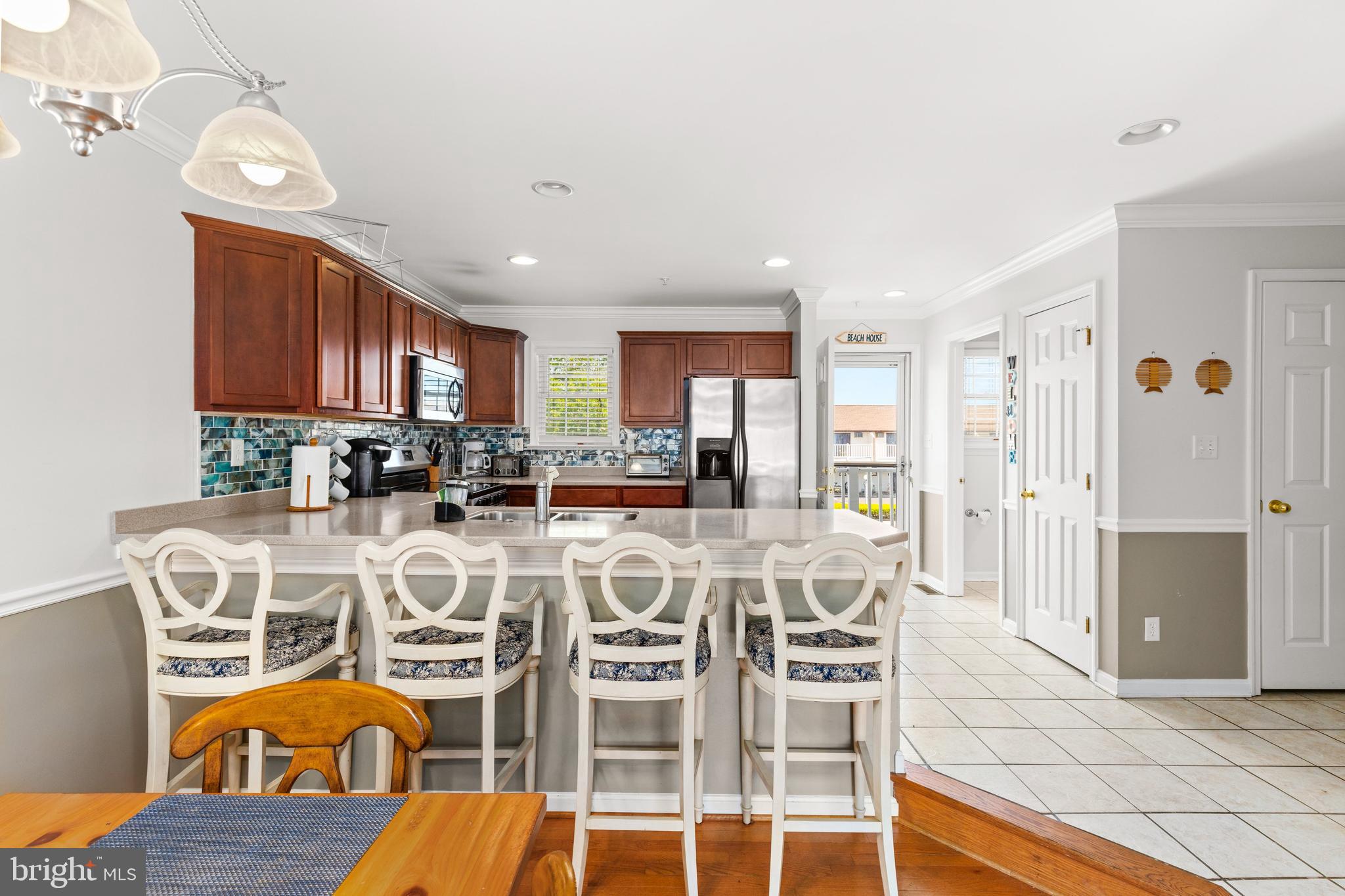 617 Salt Spray Road, Unit B Ocean City, MD 21842 - Photo 46 of 72 a view of a dining room kitchen with furniture a chandelier and wooden floor