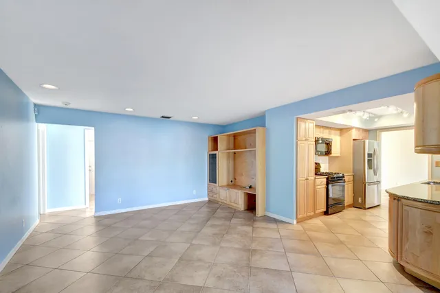 a view of an empty room with window and refrigerator