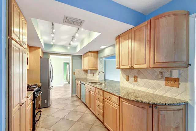 a kitchen with stainless steel appliances granite countertop a sink a stove and cabinets