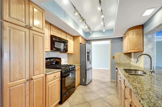 a kitchen with stainless steel appliances granite countertop a stove a sink and a microwave