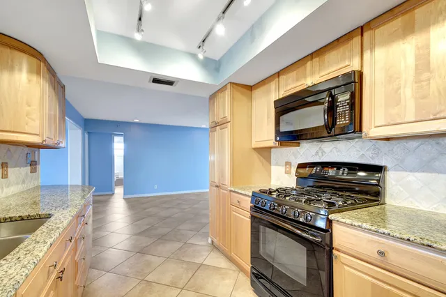 a kitchen with stainless steel appliances granite countertop a stove a sink and a microwave