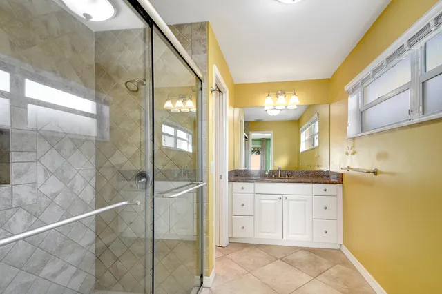 a bathroom with a granite countertop sink a mirror and a shower