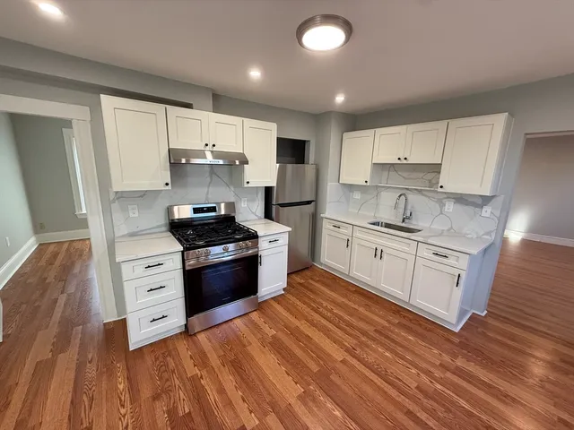 a kitchen with stainless steel appliances white cabinets a sink a stove a refrigerator and a microwave