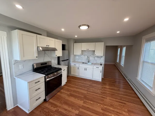 a kitchen with stainless steel appliances a white stove top oven cabinets and a wooden floor