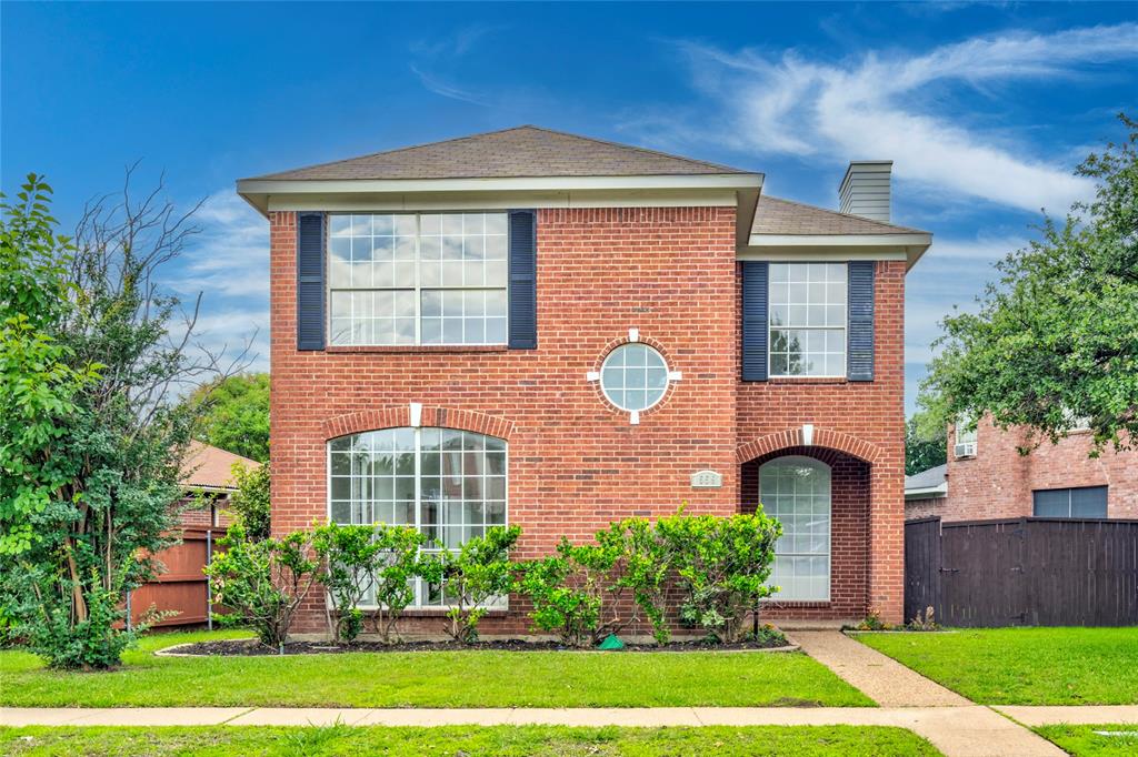 Two-story brick exterior featuring a circular window, arched entry, arched ground-floor window, and multiple upper-level windows with dark shutters