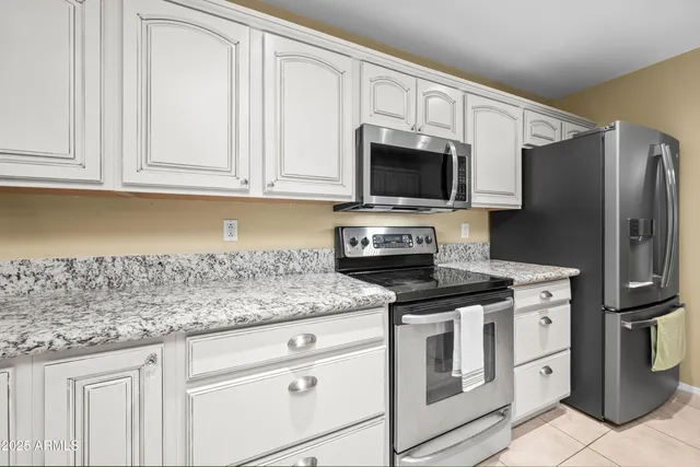 a kitchen with granite countertop white cabinets stainless steel appliances and a sink