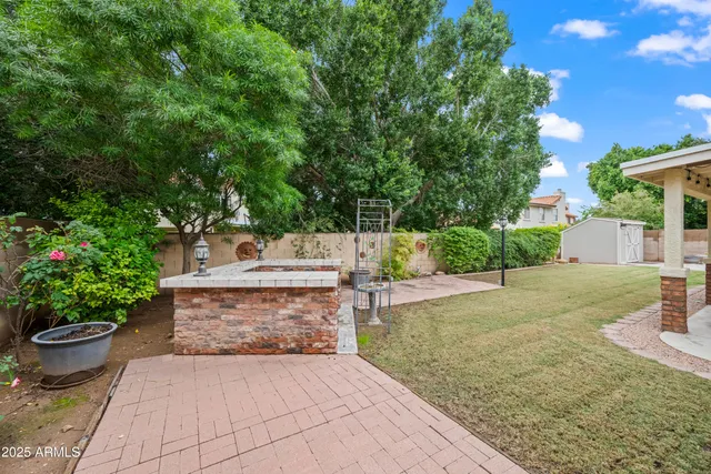 a view of a backyard with potted plants and large trees