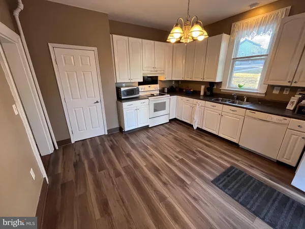 a kitchen with cabinets a sink dishwasher and a stove with wooden floor