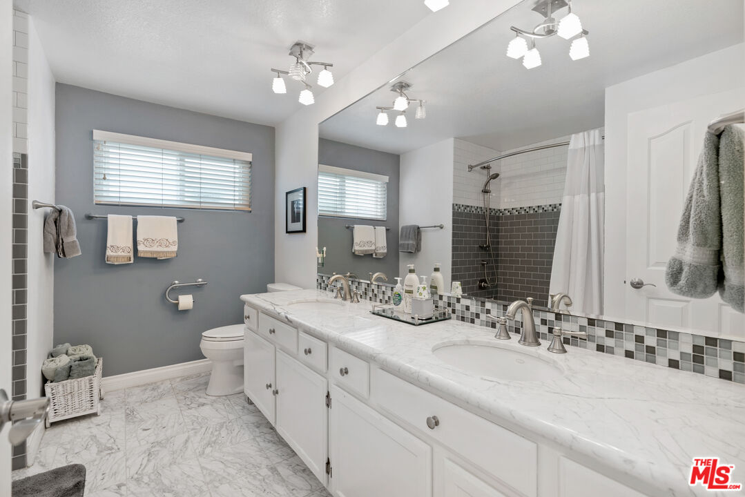 3941 Sunset Lane Oxnard, CA 93035 - Photo 15 of 24 a bathroom with double vanity sinks a toilet a mirror and window