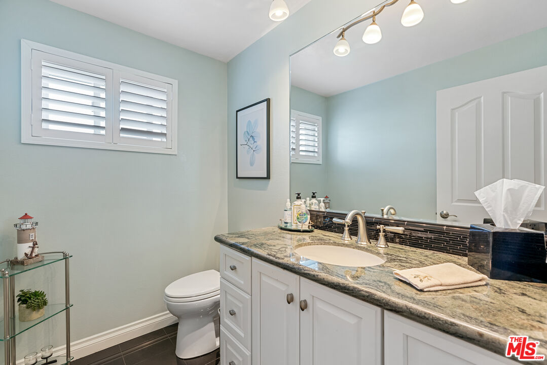 3941 Sunset Lane Oxnard, CA 93035 - Photo 21 of 24 a bathroom with a granite countertop sink a toilet and a mirror