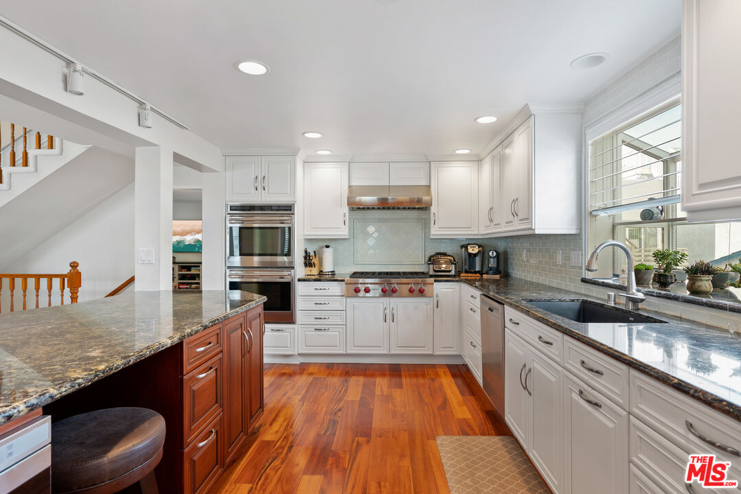 3941 Sunset Lane Oxnard, CA 93035 - Photo 6 of 24 a kitchen with stainless steel appliances granite countertop wooden cabinets a sink dishwasher a stove and a refrigerator with wooden floor