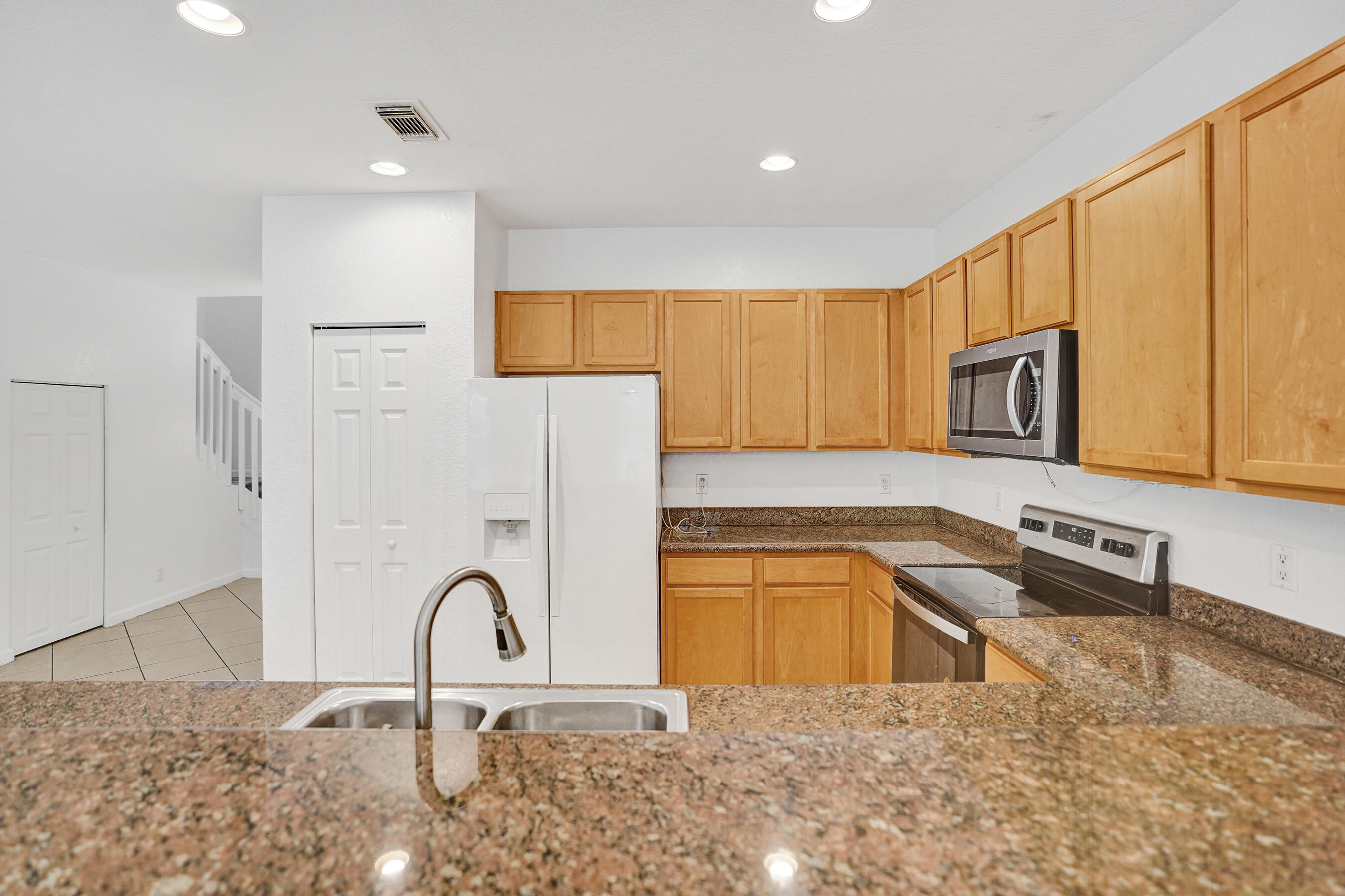 3072 North Evergreen Circle Boynton Beach, FL 33426 - Photo 19 of 55 a kitchen with stainless steel appliances granite countertop a stove top oven a sink a refrigerator with wooden cabinets and floor