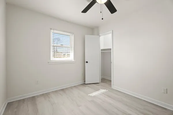 an empty room with ceiling fan and window