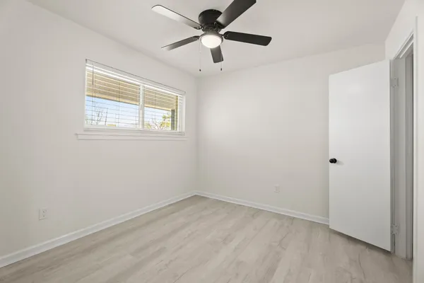 an empty room with a window and a fan