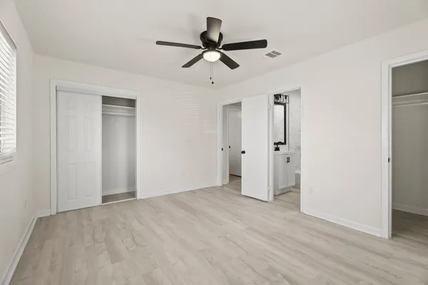 a view of empty room with wooden floor and ceiling fan