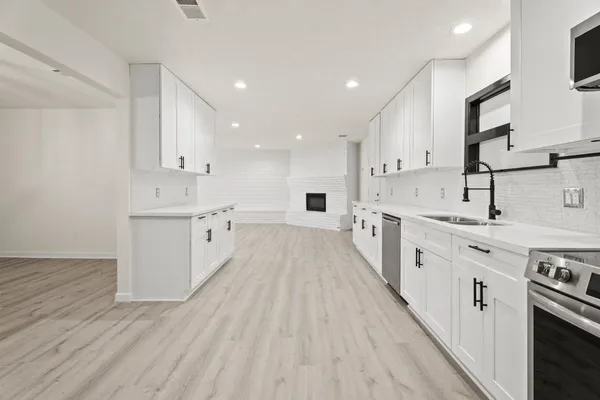 a large kitchen with stainless steel appliances and white cabinets