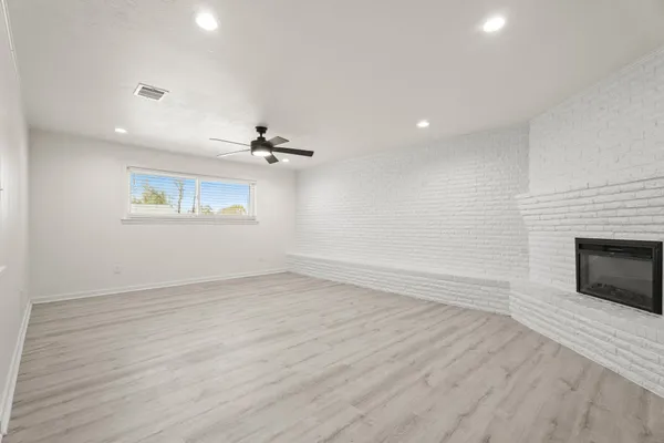an empty room with wooden floor fireplace and windows