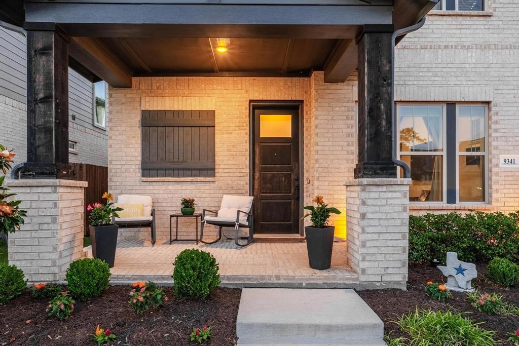 9341 Loggerhead Way Fort Worth, TX 76118 - Photo 3 of 35 Covered brick porch featuring dark wood-finish columns, a solid wood-finish entry door with clear glass panels, and horizontal wood shutters