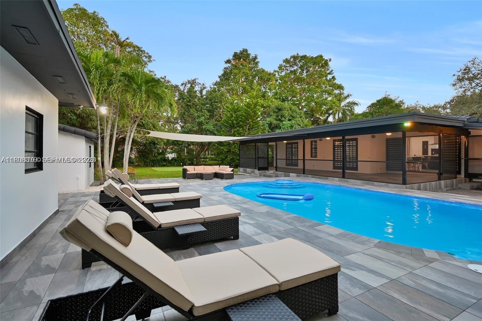 7335 Southwest 104th Street Pinecrest, FL 33156 - Photo 4 of 36 a view of a patio with couches table and chairs with wooden floor and fence