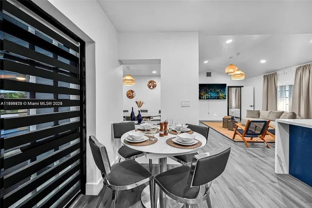 a view of a dining room and livingroom with furniture wooden floor a rug and a chandelier