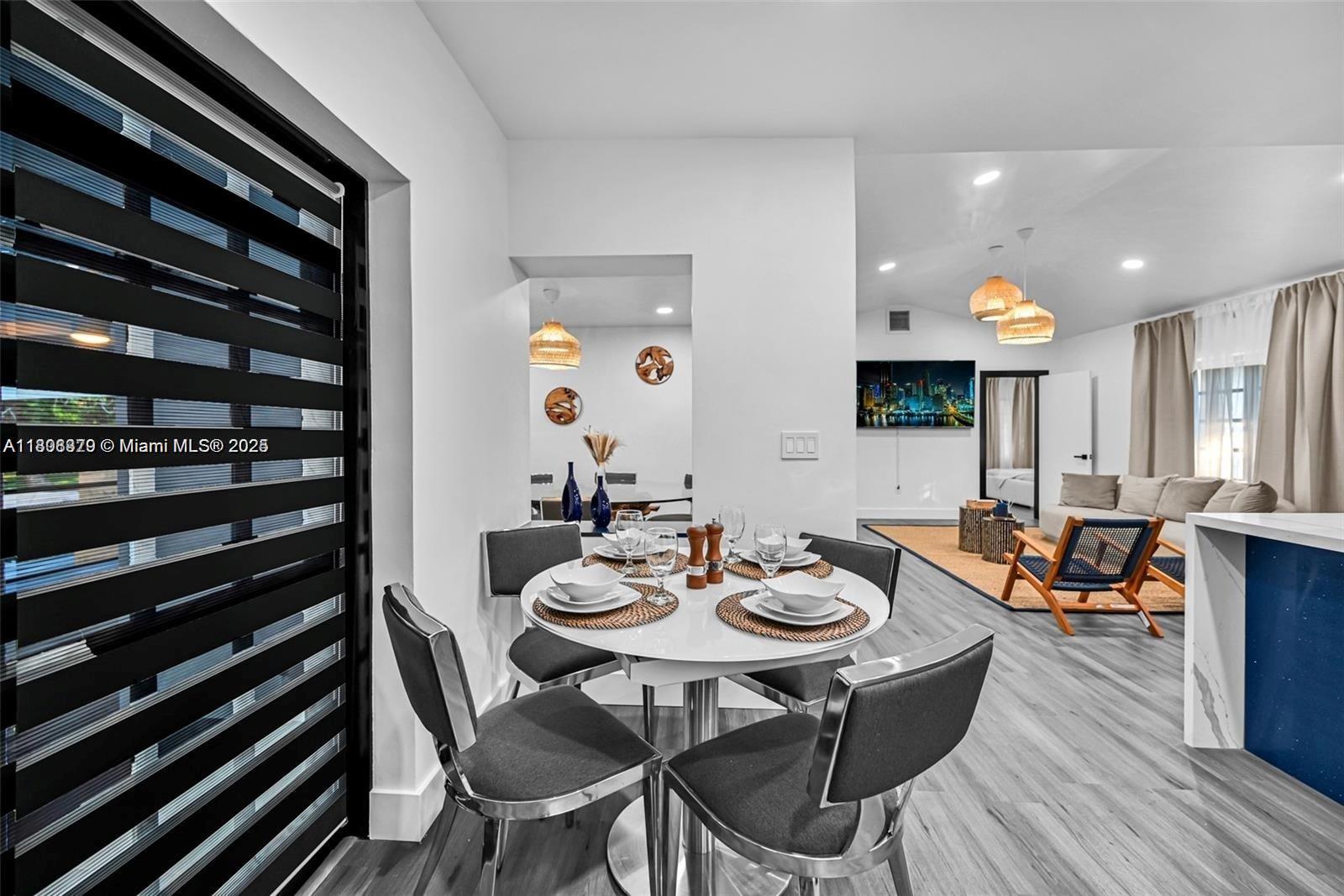 7335 Southwest 104th Street Pinecrest, FL 33156 - Photo 10 of 36 a view of a dining room and livingroom with furniture wooden floor a rug and a chandelier