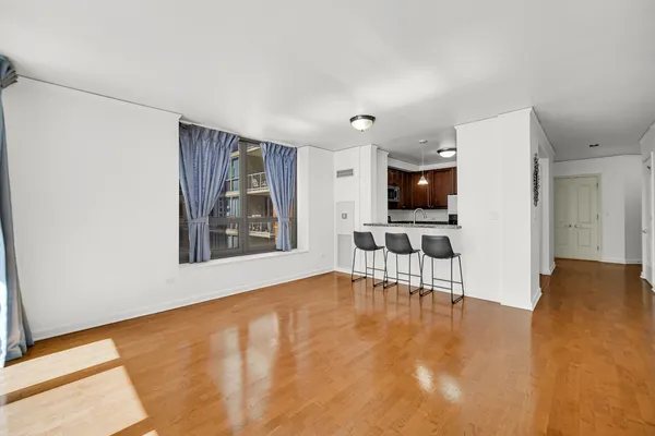 a view of an empty room with a window and kitchen view