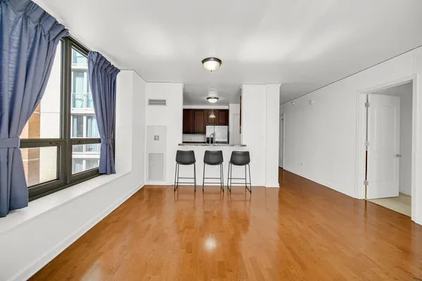 a view of an empty room with a window and wooden floor