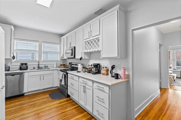 a kitchen with white cabinets appliances and a window