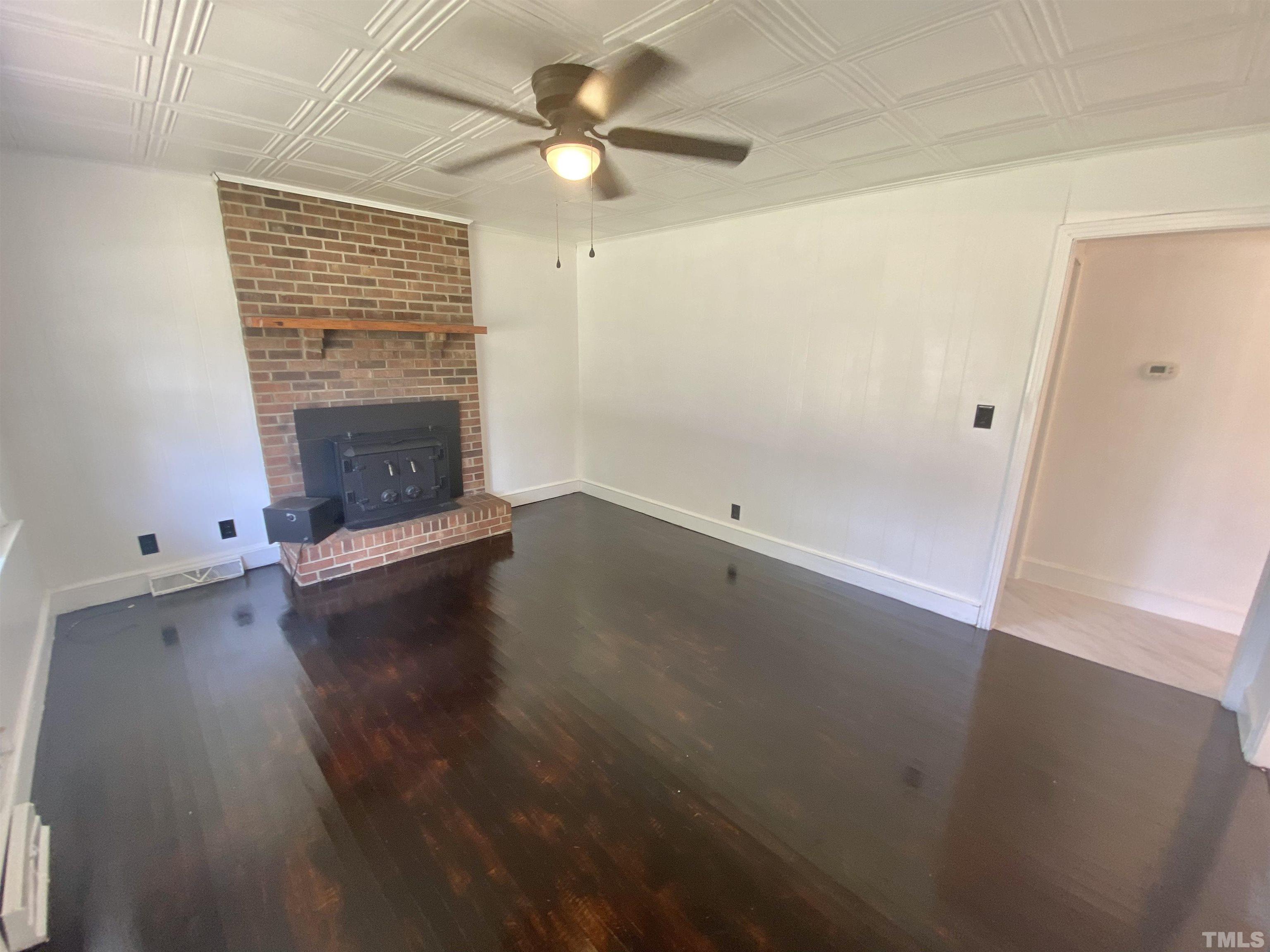302 Allgood Street Roxboro, NC 27573 - Photo 10 of 30 an empty room with a fireplace and wooden floor