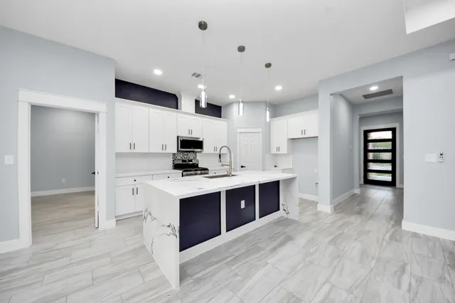 a view of kitchen with stainless steel appliances granite countertop a sink and refrigerator