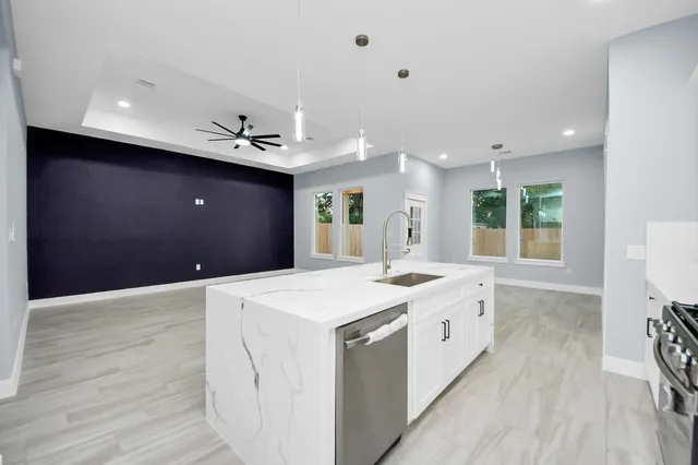 a large kitchen with stainless steel appliances kitchen island a large counter top and a wooden floors