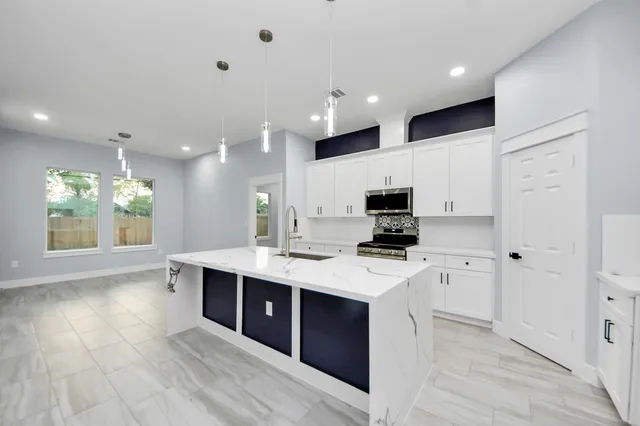a large kitchen with stainless steel appliances a sink and cabinets