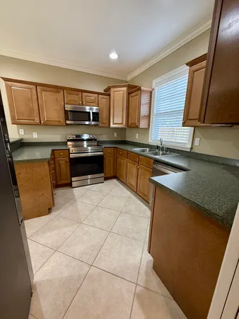 a large kitchen with stainless steel appliances granite countertop a stove top oven a sink a counter space and cabinets