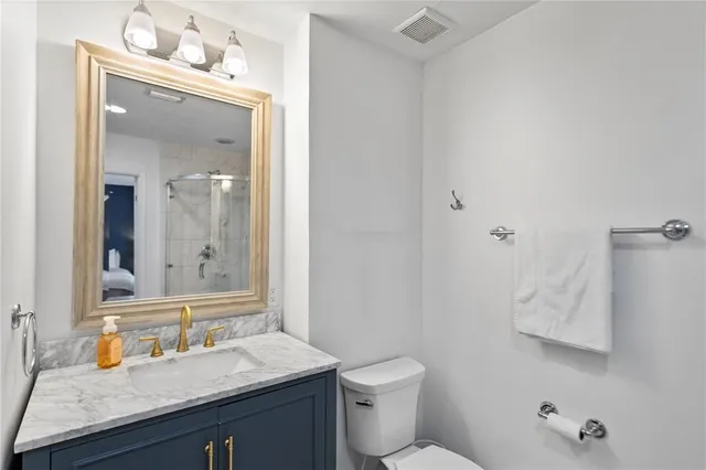 a bathroom with a granite countertop sink toilet and mirror