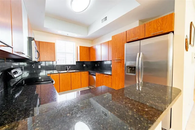 a kitchen with stainless steel appliances granite countertop a sink a stove and a refrigerator