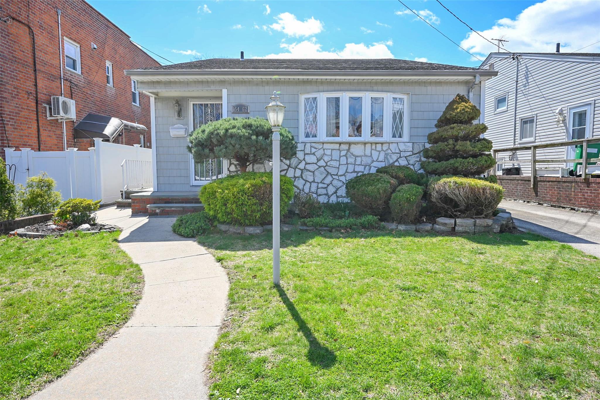 154-62 20th Road Queens, NY 11357 - Photo 1 of 1 Bungalow-style house featuring stone siding, fence, and a front lawn