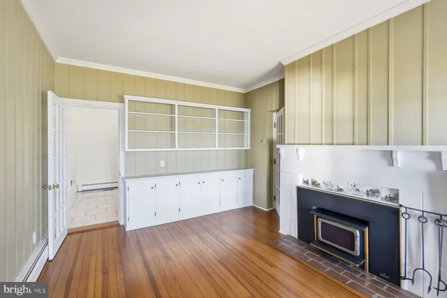 an empty room with windows a fireplace and wooden floor