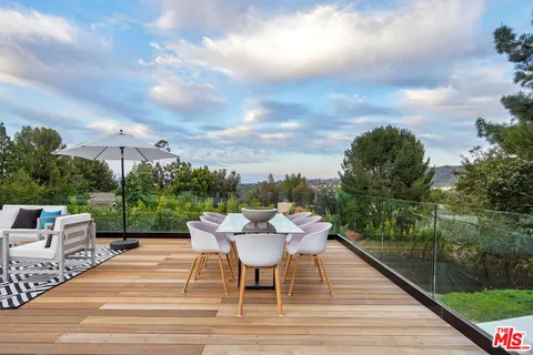 a view of a patio with couches potted plants and a big yard