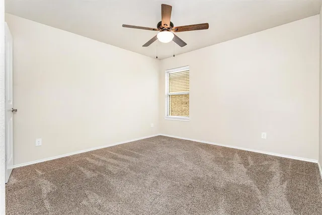 an empty room with a window and a ceiling fan