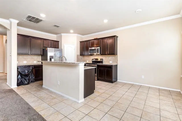 a kitchen with stainless steel appliances kitchen island granite countertop a sink a stove a microwave a dining table and chairs