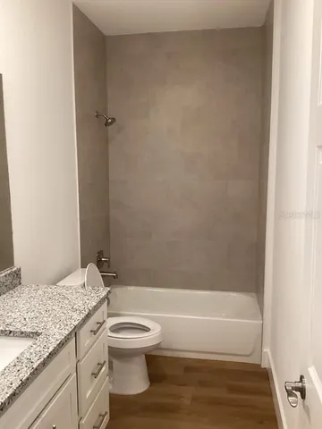 a bathroom with a granite countertop toilet a sink and bathtub