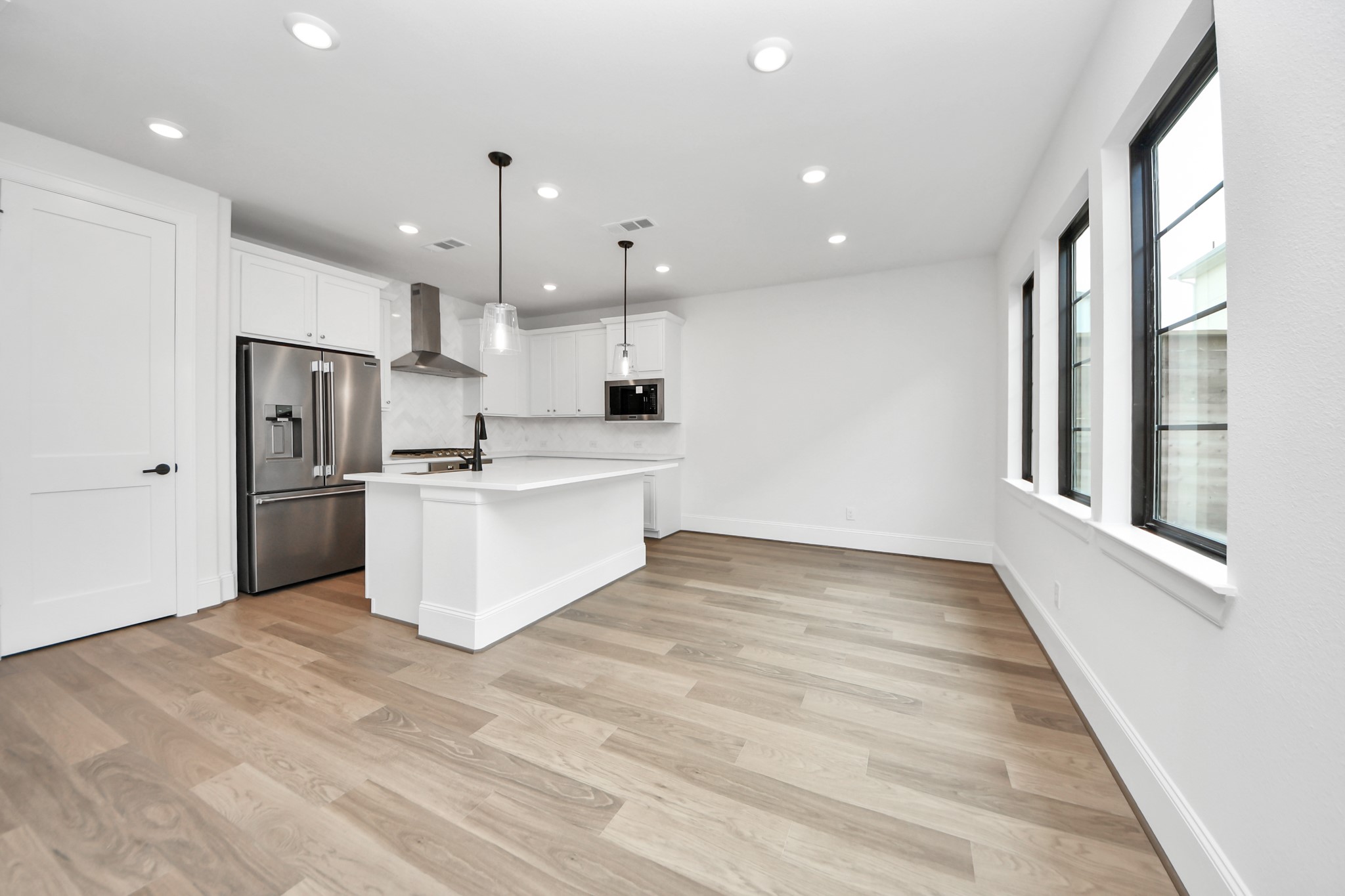 12010 Royal Oaks Banner Way Houston, TX 77082 - Photo 13 of 43 a large white kitchen with kitchen island a stove a sink dishwasher a refrigerator and white cabinets with wooden floor
