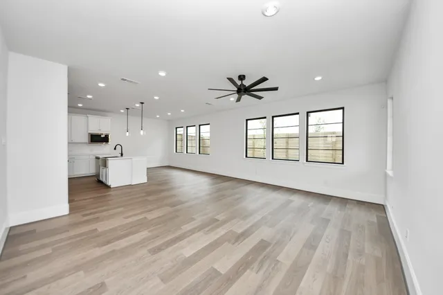 a view of an empty room with a window and wooden floor