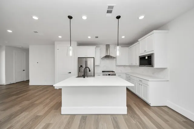 a large kitchen with stainless steel appliances a large center island attached withe living room